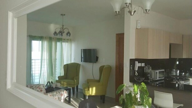 Una sala de estar con dos sillones, un televisor y un comedor con mesa y sillas.
