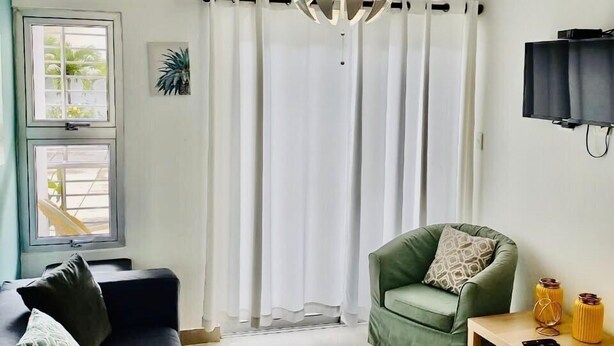 A modern living room with a black sofa, a green armchair, a wooden side table, and a unique spherical chandelier. - Comfortable 3 Rooms with pool, Wifi, 1st level (Santiago De Los Caballeros)
