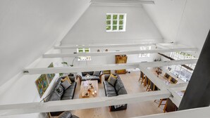 A spacious loft with a high ceiling, exposed wooden beams, a dining area with a long table, and a seating area with sofas and a coffee table. - Gorgeous home in Bogense with WiFi (Bogense)