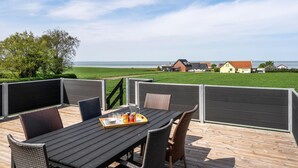 An outdoor dining area with a table and chairs, a tray with drinks, and a view of houses and a body of water. - Gorgeous home in Bogense with WiFi (Bogense)