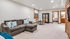 A living room with a sectional sofa, a dining table with chairs, a cabinet, and a television.