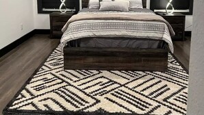 Une chambre à coucher comprenant un lit, deux tables de chevet, un ventilateur de plafond et un tapis à motifs.