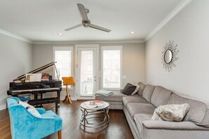 Relax in this stylish living room with a grand piano, comfortable sofa, and armchair.