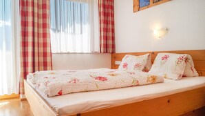 Une chambre à coucher avec un lit en bois, une literie à motifs floraux et une fenêtre avec des rideaux.