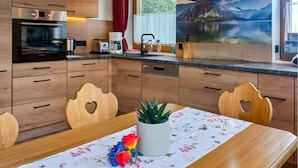 Une cuisine moderne avec des meubles en bois, un four encastré et un coin repas avec une table mise pour deux personnes.