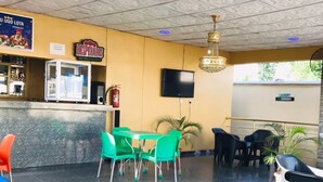 A restaurant with a tiled floor, green and blue chairs, a TV mounted on the wall, and a sign indicating a laundry service. - T Golden Villa Hotel (Enugu)