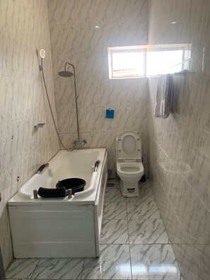 A bathroom with a bathtub, toilet, and a shower. - T Golden Villa Hotel (Enugu)