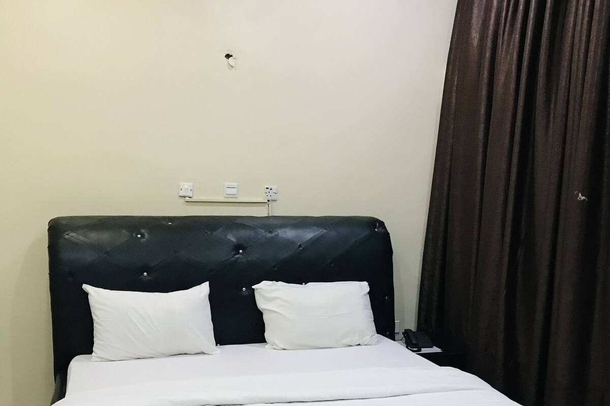 A neatly made bed with white linens in a hotel room.