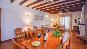 Un coin repas avec une table en bois, des chaises et une bouteille de vin.