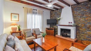 Un salon chaleureux avec une cheminée, des fauteuils confortables et un téléviseur.