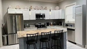 Een moderne keuken met een centraal eiland, roestvrijstalen apparatuur en witte kasten.