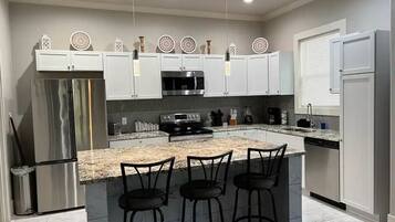 A modern kitchen with a central island, stainless steel appliances, and white cabinetry.