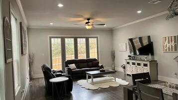 A living room with a sofa, chairs, a coffee table, and a TV.