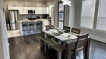 A modern kitchen with white cabinets, stainless steel appliances, and a dining area with a wooden table and chairs.