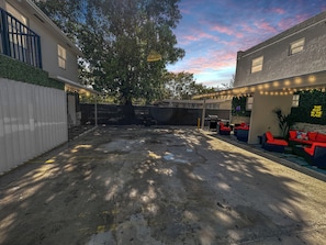 A backyard with a tree, outdoor seating, and string lights.