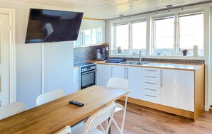 A compact kitchen with a dining area, a TV mounted above the counter, and a window providing natural light. - 2 bedroom amazing apartment in Visby (Visby)
