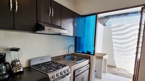 A compact kitchen with dark cabinets, a gas stove, a built-in oven, a sink, and a coffee maker.