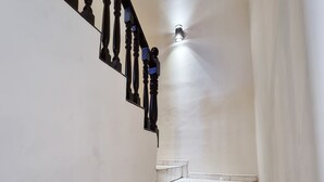 A staircase with a handrail, light fixture, and tiled steps.