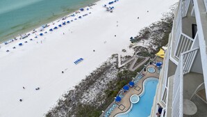 An aerial view of a beach with a pool area and a building with balconies.