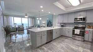 A modern kitchen with a central island, stainless steel appliances, and a view to the outside.