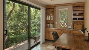 Una cocina moderna con armarios de madera, una mesa de comedor y un amplio ventanal corredero que da a un jardín.