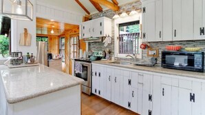 A modern kitchen with white cabinets, a granite countertop, and wooden beams on the ceiling.