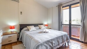 A bedroom with a bed, nightstands, a lamp, and a window with curtains. - Matilde Graceful House (Quartu Sant'Elena)