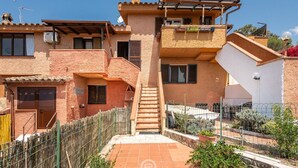 A multi-story house with a staircase leading to the upper floor, surrounded by a fenced garden area. - Matilde Graceful House (Quartu Sant'Elena)