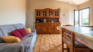 A cozy living room with a sofa, a wooden cabinet, and a dining table. - Matilde Graceful House (Quartu Sant'Elena)