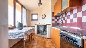 A kitchen with a tiled backsplash, a stove, and a window. - Matilde Graceful House (Quartu Sant'Elena)