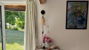 Un comedor con una mesa de madera, sillas, un florero con flores, una botella de vino y un cuadro en la pared.