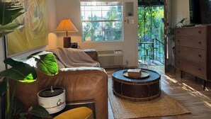 A living room with a sofa, a drum table, a lamp, and a television. - spicewood: w/pool, hot tub, relaxing courtyard (Houston)