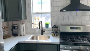 A modern kitchen with a central island, stainless steel appliances, and a window providing natural light. - spicewood: w/pool, hot tub, relaxing courtyard (Houston)