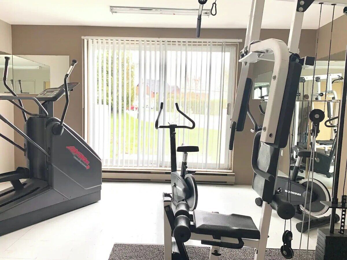 Ein Heimfitnessraum mit Laufband, Crosstrainer und Kraftmaschine.