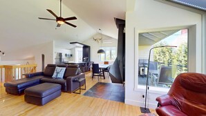 Amplia sala de estar con cocina moderna, comedor y un ventanal con vista a una terraza.