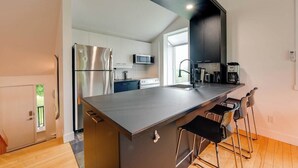 Una cocina moderna con una isla central, electrodomésticos de acero inoxidable y taburetes de bar.