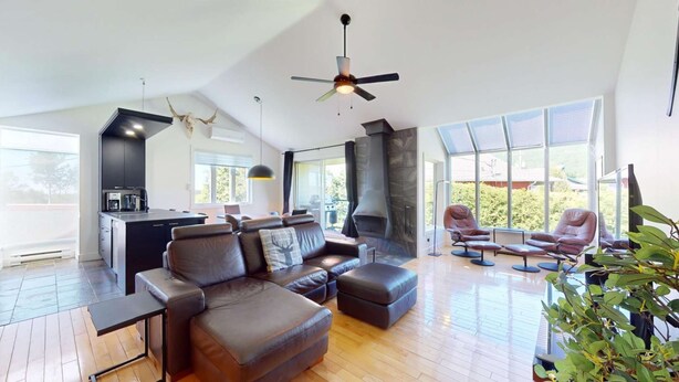 Un amplio salón con cocina moderna, chimenea y un gran ventanal con vistas al exterior.