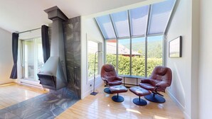 Una sala de estar moderna con chimenea, ventanas amplias y sillones de cuero.