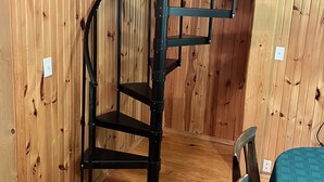 Un escalier en colimaçon dans une pièce en bois, avec une petite table et une chaise.