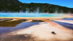 Una fuente termal geotérmica con depósitos minerales y vapor saliendo del agua.