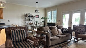 A living room with wicker furniture, a brown sofa, and striped cushions. - Lakeside Condo ~ Close to Everything ~ First Floor ~ Pool ~ Dock ~ Views (Guntersville)
