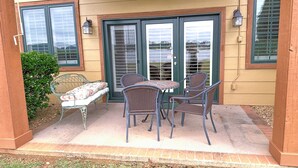 An outdoor patio with a table and chairs, a bench, and a small garden area. - Lakeside Condo ~ Close to Everything ~ First Floor ~ Pool ~ Dock ~ Views (Guntersville)