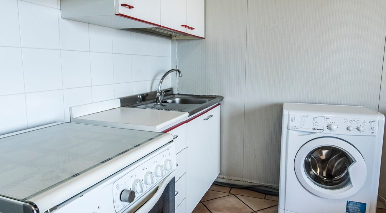 A kitchen with a stove, sink, and a washing machine.