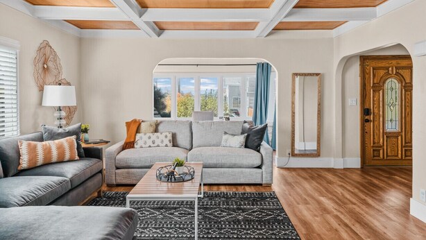 A living room with a grey sofa, a wooden coffee table, and a patterned rug.