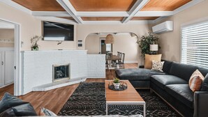 A modern living room with a fireplace, a dining area, and a kitchen.