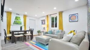 A modern living room with a dining area, a sofa, and a colorful striped rug. - 4 to 14 Guests 2 Kitchens Deco Retreat BBQ Patio (Miami)