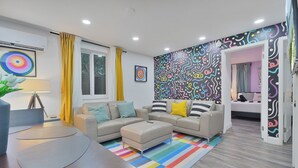 A modern living room with a sofa set, a coffee table, and a colorful striped rug. - 4 to 14 Guests 2 Kitchens Deco Retreat BBQ Patio (Miami)