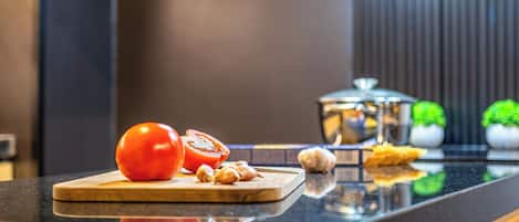 A kitchen counter with a cutting board holding a tomato, garlic, and a knife.