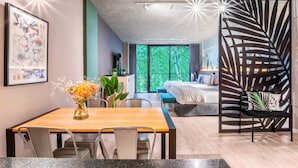 A modern hotel room with a dining area, a large window with a view of greenery, and a decorative plant on the table. - Deluxe Apartments in Palermo - by BueRentals (Buenos Aires)