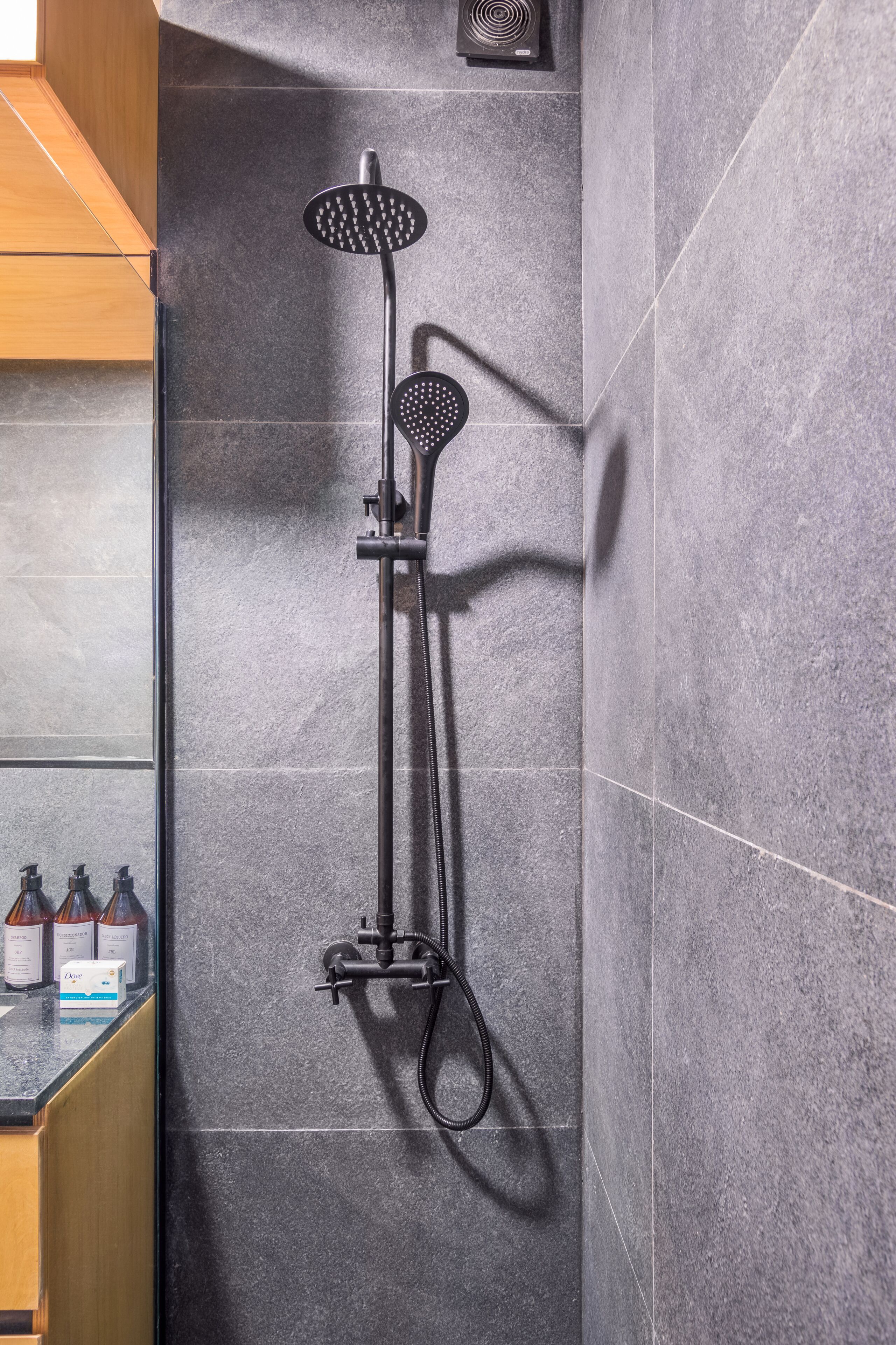 A modern shower with a handheld showerhead and a wall-mounted faucet.